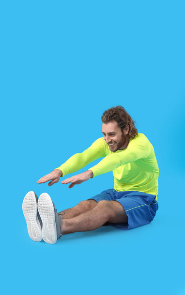 Sporty man stretching on blue background - Photo, Image