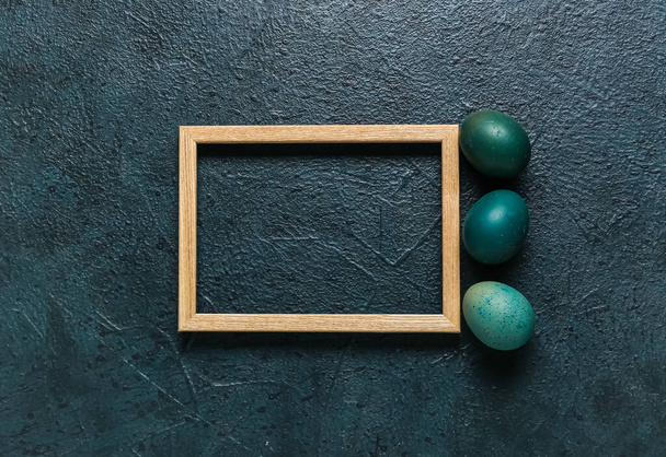 Composition with wooden photo frame and Easter eggs on dark background - Fotografie, Obrázek