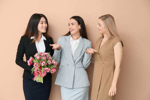 Schöne Frauen mit Blumenstrauß auf farbigem Hintergrund. Feier zum Internationalen Frauentag - Foto, Bild