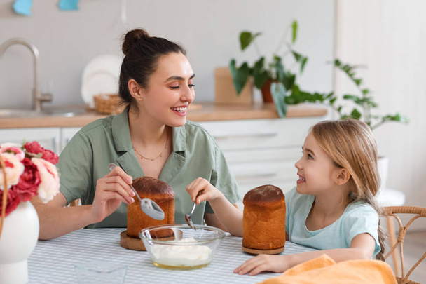 Маленькая девочка и ее мать с вкусными пасхальными тортами дают друг другу пять на кухне - Фото, изображение