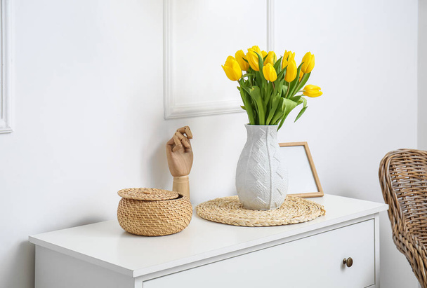 Cesta de vime, mão de manequim e vaso com tulipas perto da parede branca - Foto, Imagem