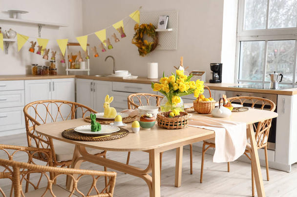 Festliche Tischdekoration mit gelben Tulpen und Osterhasen in Küche - Foto, Bild