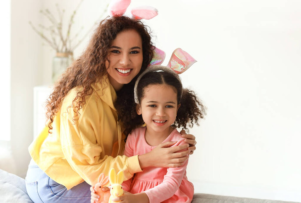 Pieni afroamerikkalainen tyttö pääsiäiskanien ja hänen äitinsä kanssa kotona - Valokuva, kuva