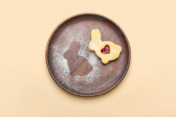 Assiette avec délicieux biscuit de Pâques en forme de lapin sur fond beige - Photo, image