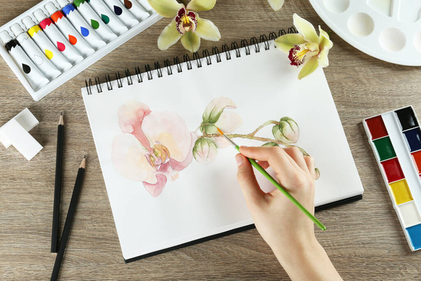 Woman drawing beautiful orchid - Photo, Image
