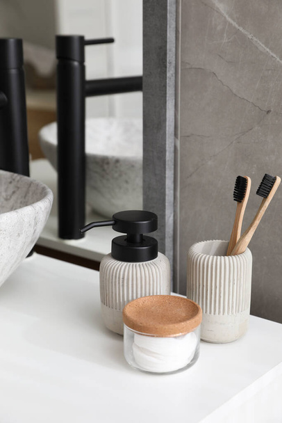 Stone vessel sink with faucet and toiletries on white countertop in bathroom - Foto, afbeelding