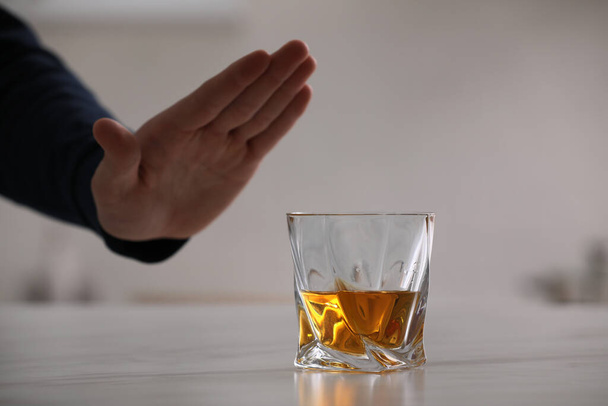 Man refusing to drink whiskey indoors, closeup. Alcohol addiction treatment - Фото, зображення