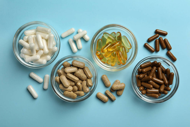 Different dietary supplements on light blue background, flat lay - Foto, imagen