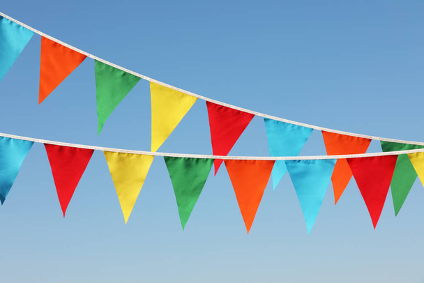 Buntings s barevnými trojúhelníkovými vlajkami proti modré obloze - Fotografie, Obrázek