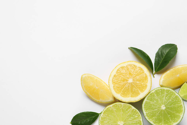 Fresh ripe lemons, limes and green leaves on white background, top view - Foto, Bild