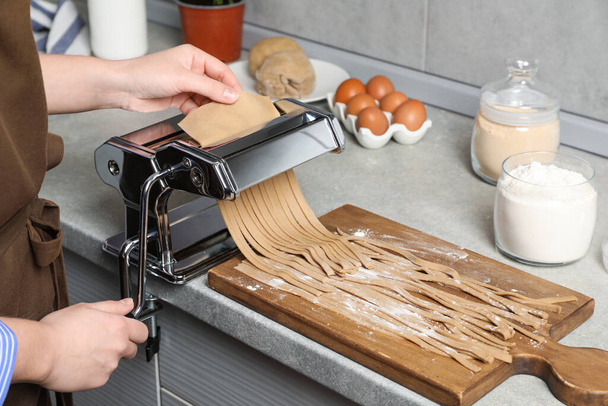 Woman making soba with pasta machine at table in kitchen, closeup - Foto, Imagem