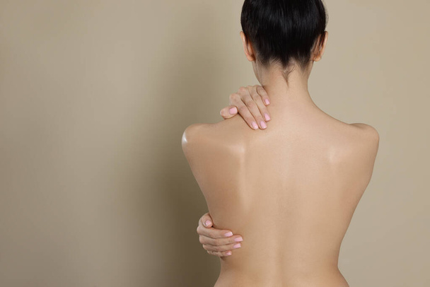 Back view of woman with perfect smooth skin on beige background, space for text - Φωτογραφία, εικόνα