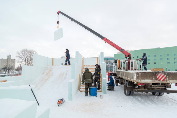 Робітники покривають каркас дерев'яної гірки льодовими панелями
 - Фото, зображення
