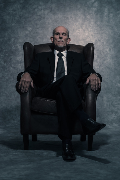 In leather chair sitting senior businessman with gray beard wear - 写真・画像