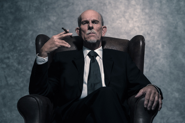 Zigarren rauchender Geschäftsmann mit grauem Bart und dunklem Hemd - Foto, Bild