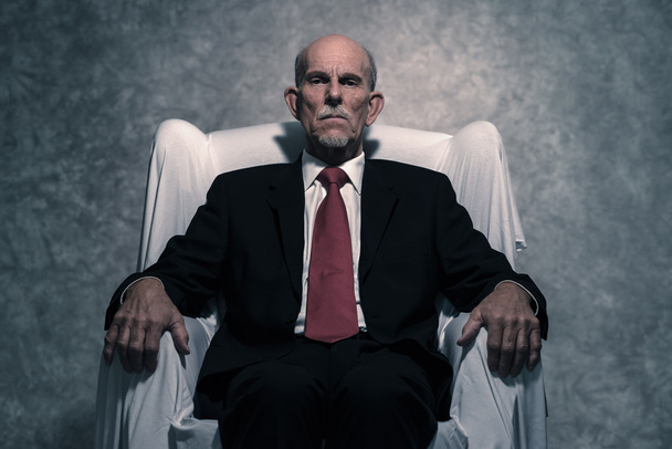 Boshafter Geschäftsmann mit grauem Bart und dunklem Anzug - Foto, Bild