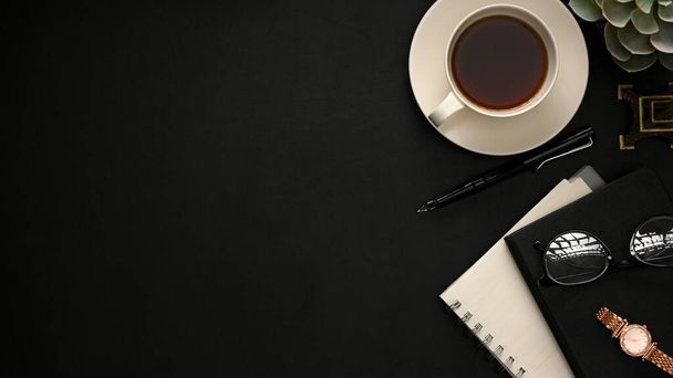 Minimaler schwarzer Arbeitsplatzhintergrund mit Kaffeetasse, Schreibwaren und Kopierraum für Produktpräsentation oder Textanzeige. über Kopf, flach gelegt - Foto, Bild