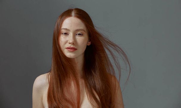 Beautiful redhead young girl with naked shoulders, waving long hairs. Ginger healthy hairs. Natural beauty - Foto, afbeelding