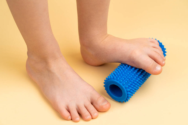 niebieski rolka igły do masażu i fizjoterapii na beżowym tle z wizerunkiem stopy dziecka, koncepcja zapobiegania i leczenia haluksów valgus - Zdjęcie, obraz