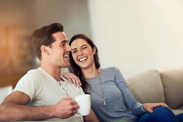 Filling their home with love and laughter. Shot of a happy young couple relaxing together at home. - Foto, Imagem