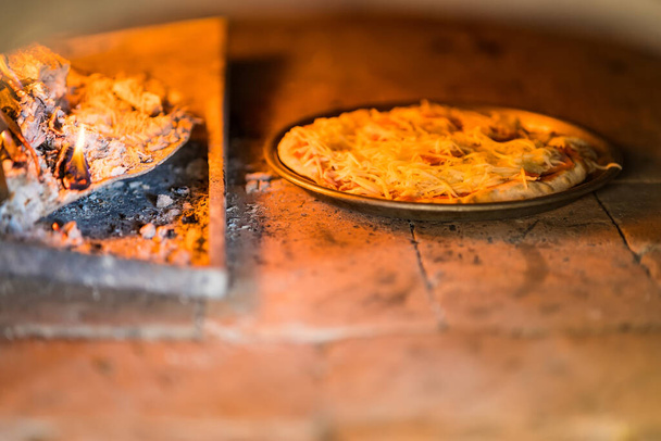 Geleneksel pişirilmiş ahşap fırın İtalyan pizza fırını pizzacısı. İtalyan pizzası ahşap fırında pişirilir. - Fotoğraf, Görsel