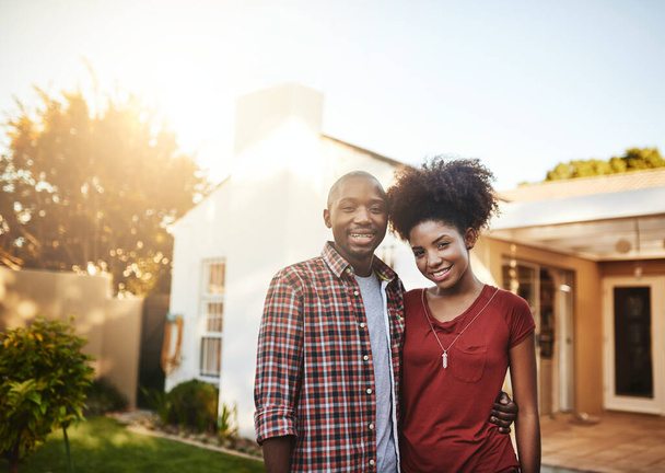 Гордый первый раз домовладелец. Портрет молодой пары, стоящей перед своим новым домом. - Фото, изображение