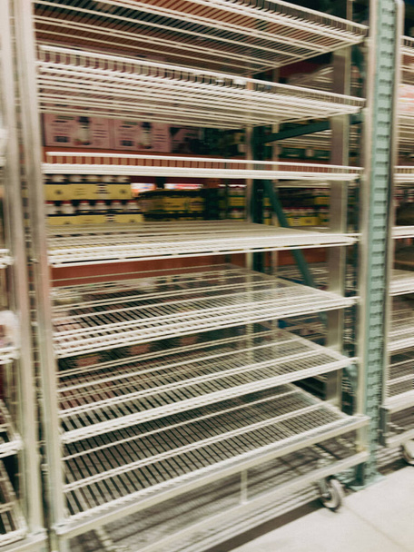 Getönte Fotos verwischen leere Regale im Großhandelsgeschäft in der Nähe von Dallas, Texas, Amerika. Supermarkt mit leeren Stahlregalen mit Rollen wegen Lebensmittelknappheit und Lieferkettenkrise - Foto, Bild