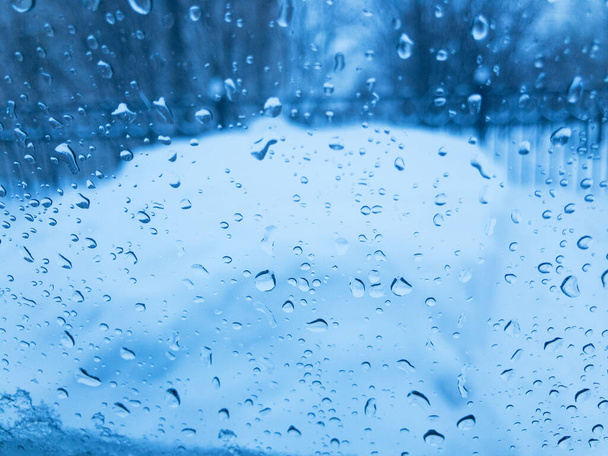 Капли конденсата на стакан с голубым оттенком зимой. - Фото, изображение