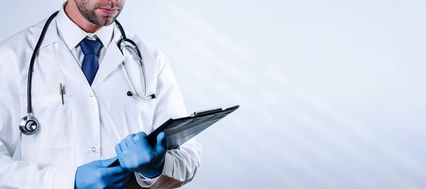 Doktor Klemmbrett medizinischen Hintergrund. Glückliche Krankenschwester in blauen Handschuhen, Krankenhausuniform mit Klemmbrett auf weißem Papier. Banner für Medizin und Gesundheitswesen - Foto, Bild