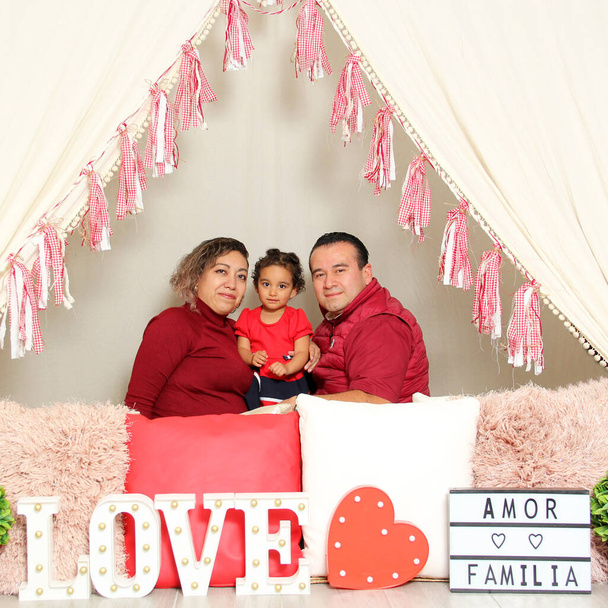 Latina mom, dad and daughter show their affection under a teepee with a sign that says "Love and family" celebrate Valentine's Day of Love and Friendship in February - Photo, Image