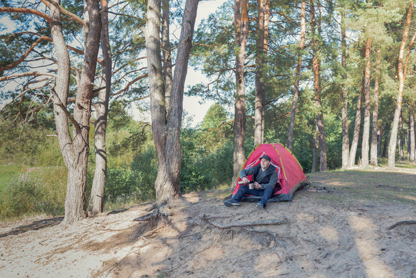 Si siede vicino alla tenda nella foresta. Campeggio all'aperto. - Foto, immagini