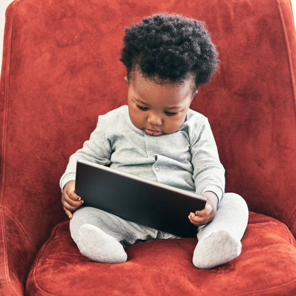 I need to check my emails.... Shot of a little baby boy sitting in a chair holding a digital tablet. - Photo, Image