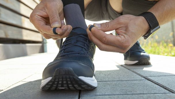 Guy preparing for running and laces up on the sneakers - Foto, Bild