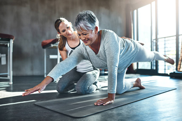Trabajar juntos para mejorar la fuerza muscular y el tono. Fotografía de una mujer mayor haciendo ejercicio con su fisioterapeuta. - Foto, imagen