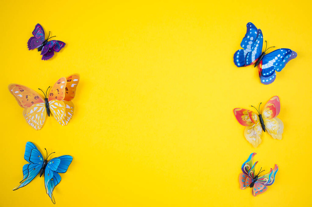 Dekorative Schmetterlinge auf leuchtend gelbem Hintergrund. Das Konzept der Frühling-Sommer-Saison. - Foto, Bild