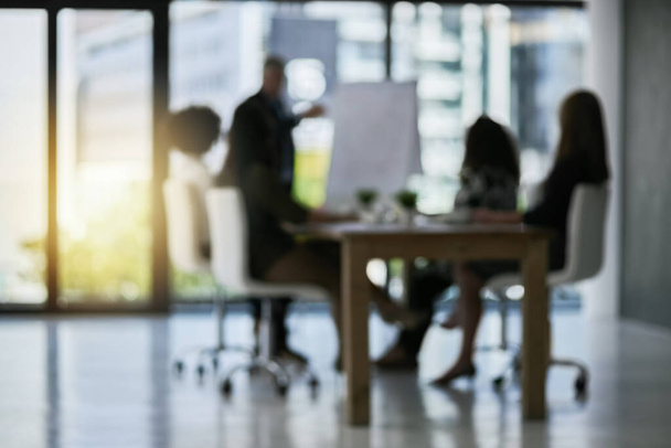 Clearing things up with a presentation. Defocussed shot of a team of businesspeople attending a meeting in the boardroom. - Photo, Image