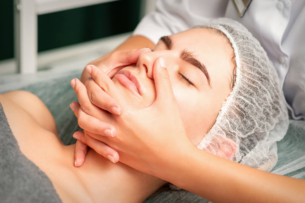 Uma jovem caucasiana recebendo massagem facial em um spa - Foto, Imagem