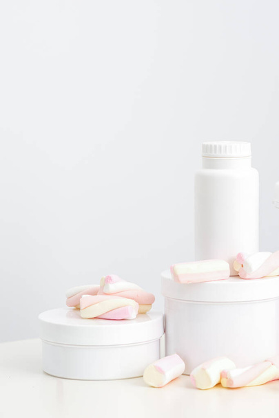 Cosmetic skincare packaging. Beauty product on white background. White jars with marshmallows on the white table - Photo, Image