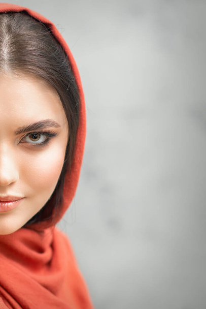 Portrait of a pretty young caucasian woman with makeup in a red headscarf on gray background - Photo, image
