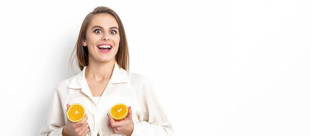 Joyeux attrayant jeune femme ayant deux morceaux d'orange isolé sur fond blanc avec espace de copie - Photo, image