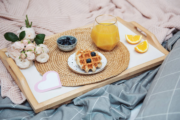 Романтический завтрак с вафлями, апельсиновым соком и цветами розы и подарочной коробкой - Фото, изображение