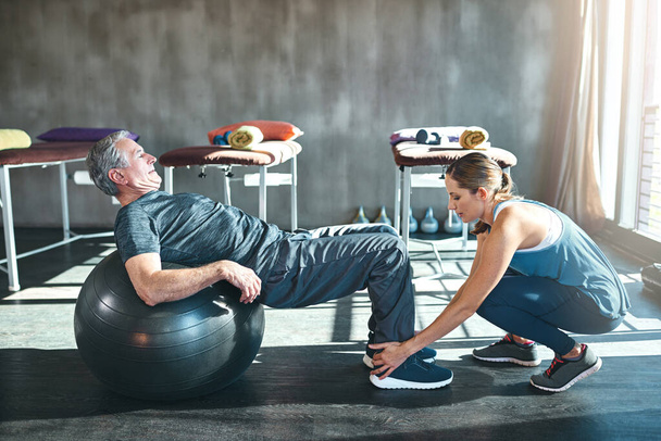 Hora de levantarse y ponerse en marcha. Una foto de un hombre mayor haciendo ejercicio con su fisioterapeuta. - Foto, imagen