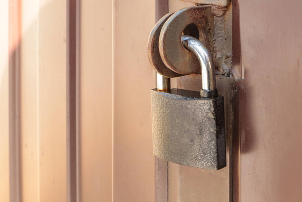 Close-up padlock on the gate of a metal brown fence made of modern siding, the concept of security. - Photo, Image