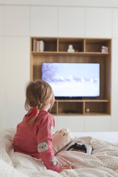 Little cute girl watching television at home. - Foto, Bild