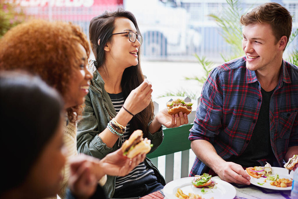 Comida rápida y amistad. Recorte de un grupo de amigos comiendo hamburguesas al aire libre. - Foto, Imagen