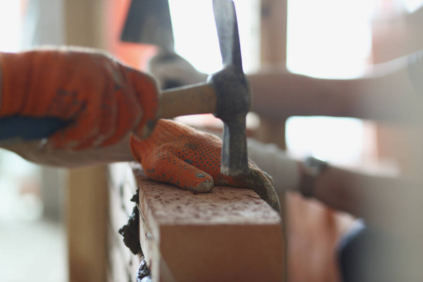 Handyman martilleo en ladrillo rojo con herramienta, el trabajador usa guantes en el trabajo - Foto, imagen