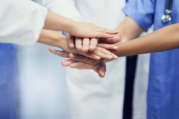 Salvar vidas juntos. Primer plano de un grupo de profesionales médicos de pie en un grupo con las manos juntas. - Foto, Imagen