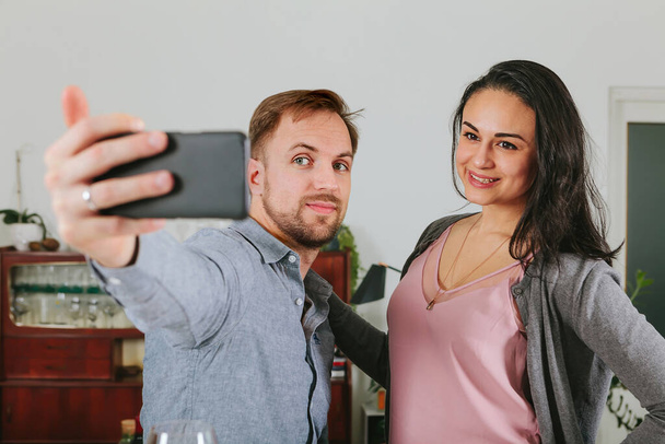 koppel neemt een selfie met smartphone thuis - plaatsen in sociaal netwerk - Foto, afbeelding