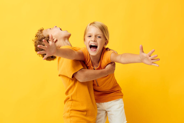 two joyful children cuddling fashion childhood entertainment on colored background unaltered - 写真・画像