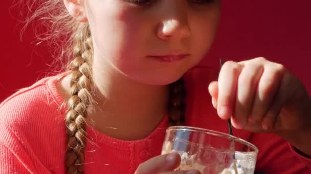 Lapsi syö jogurtti hyytelö vaaleanpunainen tausta. Maitotuote ruokavalio Lactobacillus Acidophilus, terveellinen kotitekoinen aamiainen menu. Terveydenhuolto. Vegaaninen ruoka pähkinä maito liivate ei-maitotuote jälkiruoka Proteiini vanukas - Materiaali, video